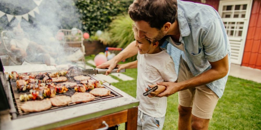A dad and his son grilling outdoors.