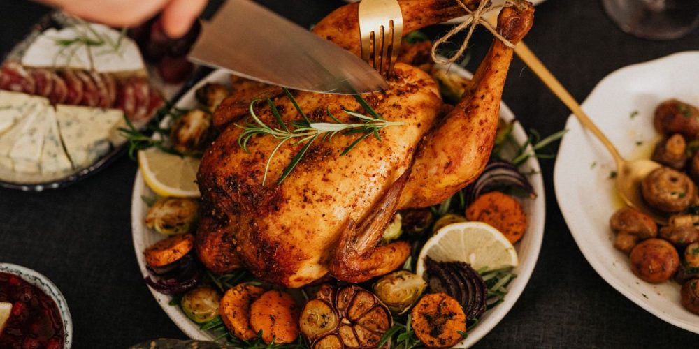 A person carving a rotisserie chicken with a sharp kitchen knife. Here are ways to make the most of a rotisserie chicken.