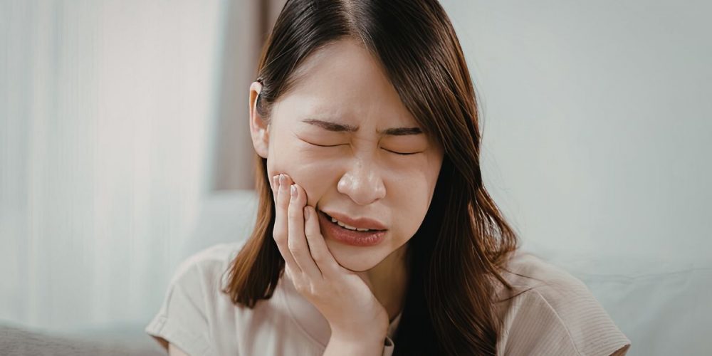 A woman visibly looking like she's in pain, particularly her tooth.