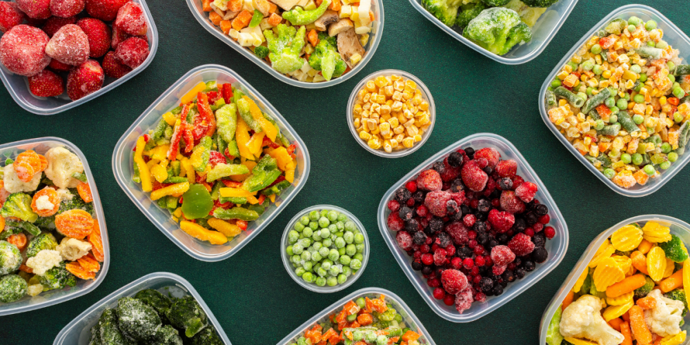 Flat lay shot of an assortment of frozen Fall produce, on an evergreen surface.