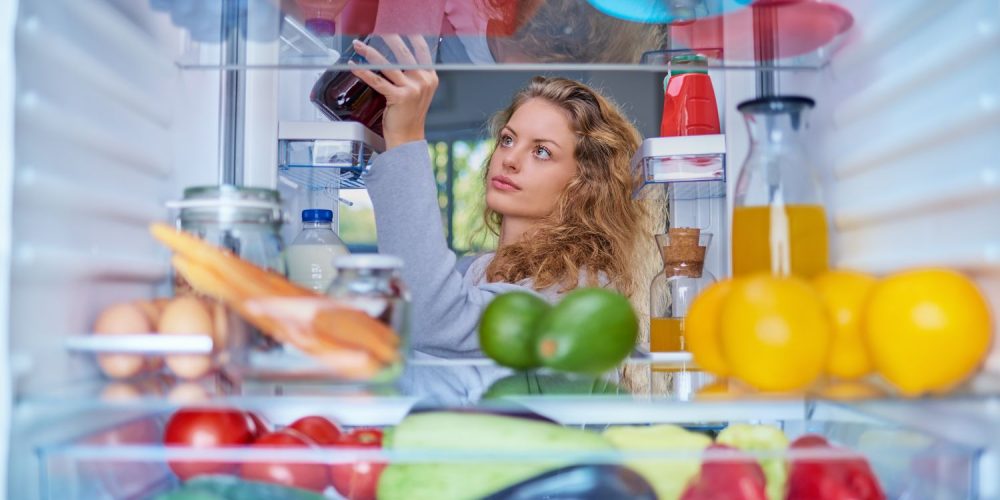 A woman taking a bottled juice out of the fridge.