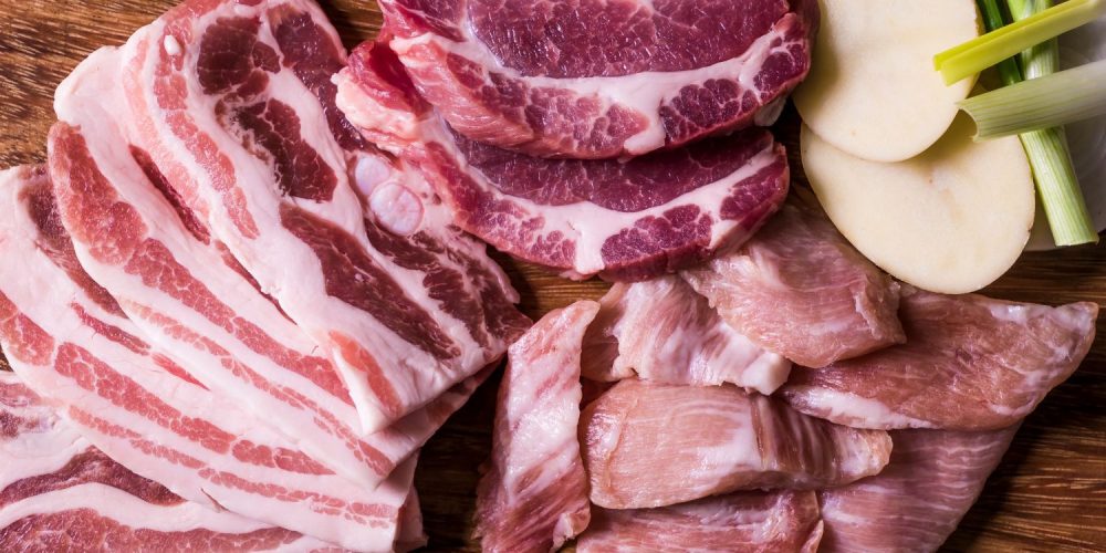 Flat lay shot of raw meat on a wooden surface.