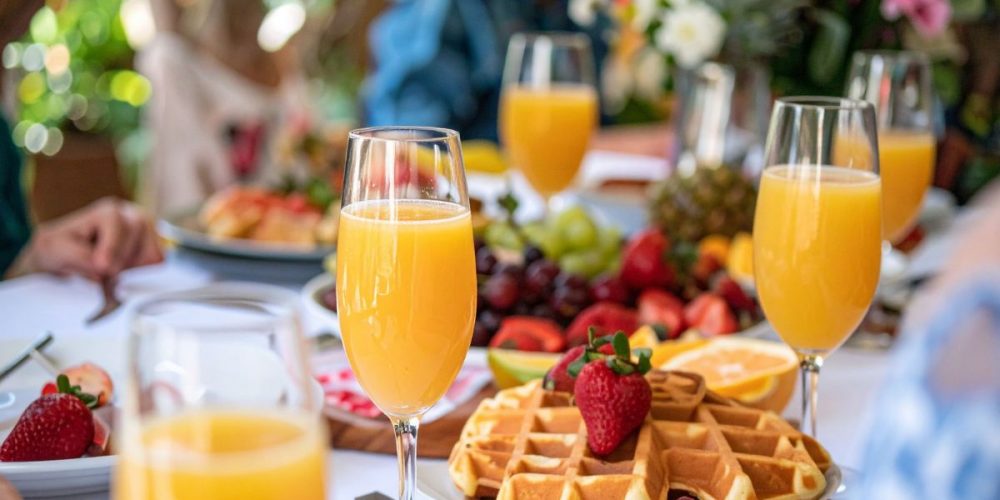 Focus shot on a brunch spread with waffles, pastries, fruits and fresh orange juice.