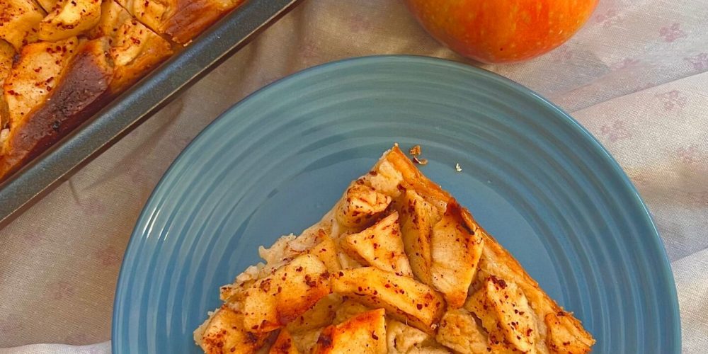 Baking dish of golden baked apple French toast with a whole apple beside it