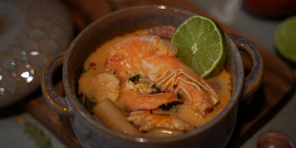 Delicious homemade Thai Tom Yum soup featuring fresh shrimp and tangy lime in a ceramic bowl.