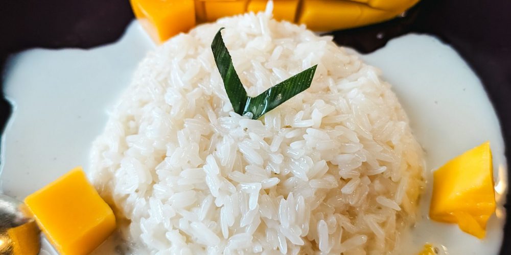Delicious Thai dessert featuring ripe mango and sticky rice topped with coconut sauce.