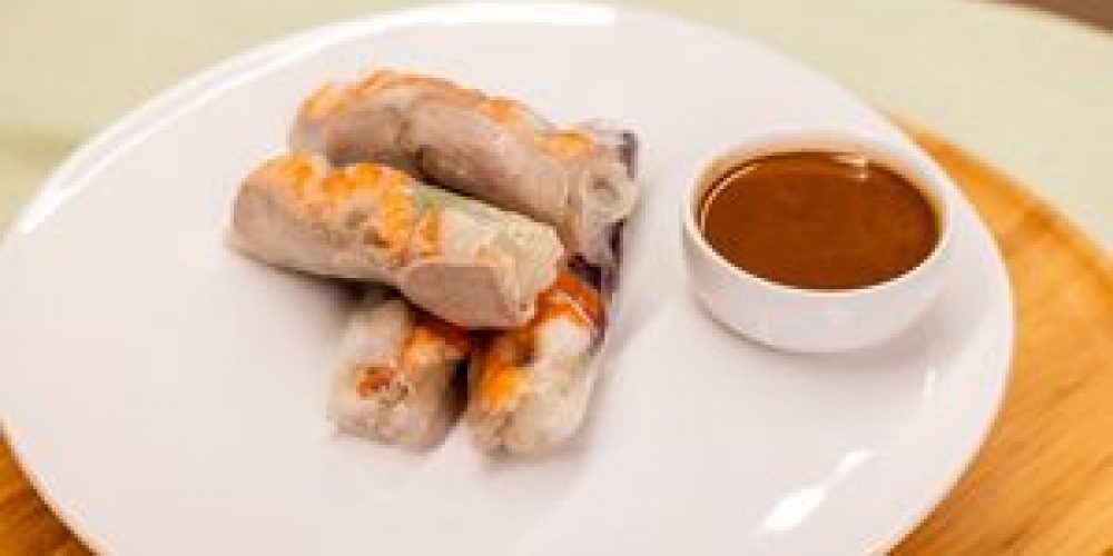Delicious Vietnamese spring rolls served with savory dipping sauce on a white plate.