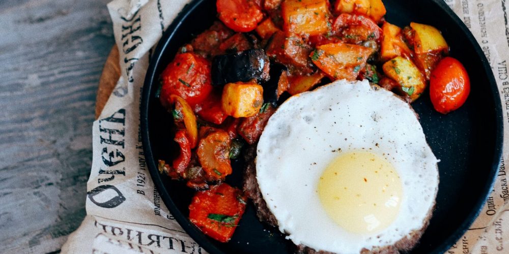 Cast iron skillet of crisp potato hash with a fried egg on top