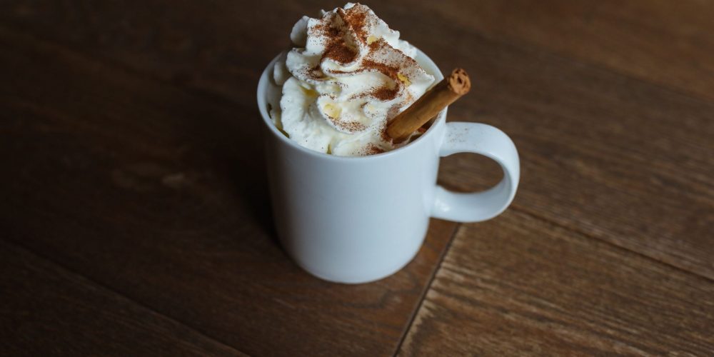 Homemade pumpkin spice latte in a white mug topped with whipped cream and cinnamon
