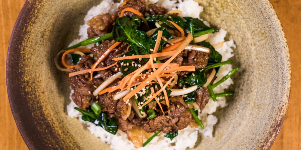 Deliciously vibrant Korean bibimbap topped with marinated bulgogi beef and fresh vegetables.