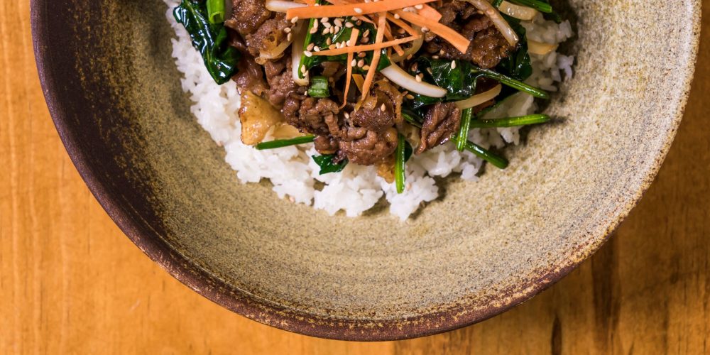 Authentic Korean Bibimbap with fresh vegetables and beef served in a rustic bowl.