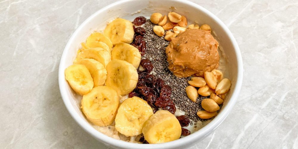 Bowl of overnight oats topped with banana slices, peanuts and peanut butter