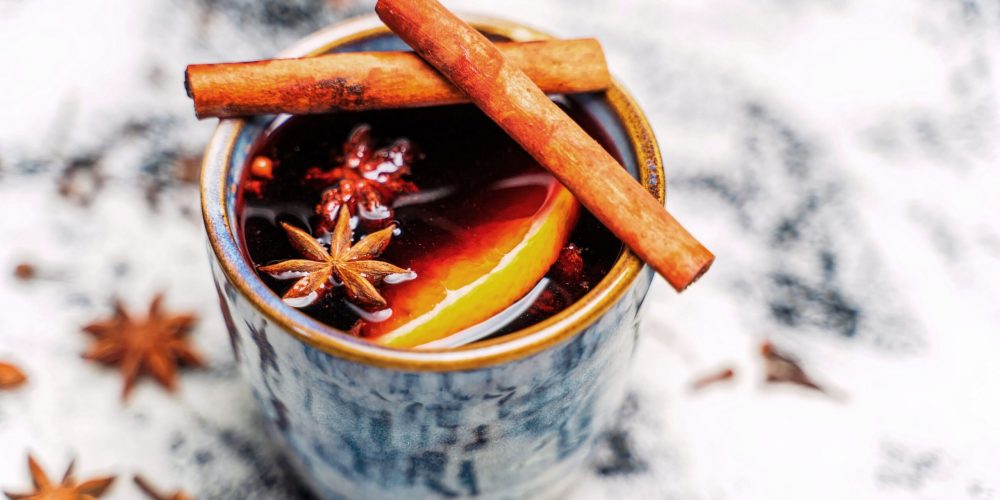 Mug of slow cooker mulled red wine punch garnished with cinnamon sticks, star anise and an orange slice