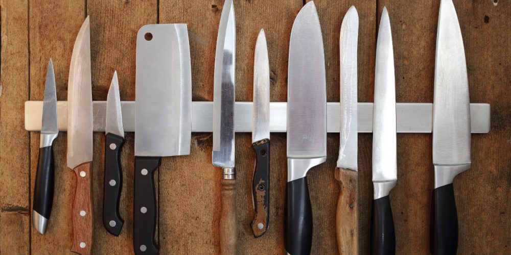 Flat lay shot of a row of kitchen knives on a magnetic rack.